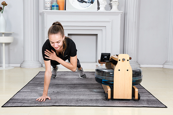 a woman doing single arm plank beside a blue-dyed rowing machine in a room