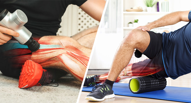 One man sitting on the ground uses a massage gun to do a deep tissue massage for the muscles around his knee and another man sitting on a blue mat massages his thigh with a foam roller.