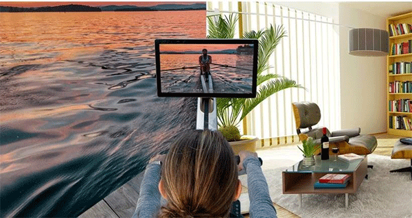 one person looks at the monitor screen in a living room and another person in the screen rows on a lake