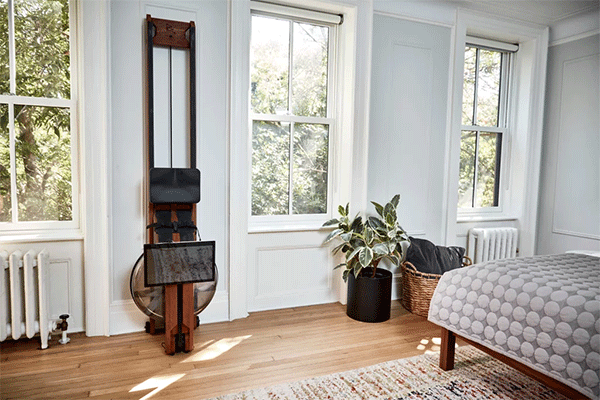Ergatta water rowing machine placed against a wall beside a window in a bedroom