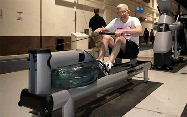 a man with white hair rows with a water rowing machine