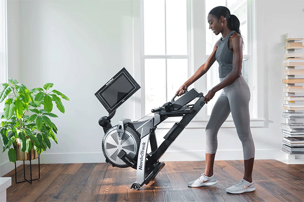 A woman in black skin folds a NordicTrack RW700 rowing machine