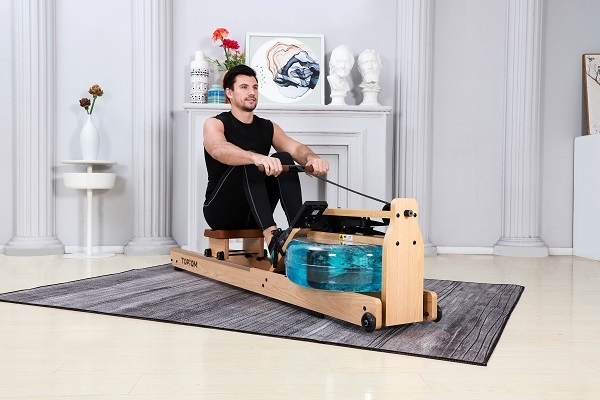 a man wearing black clothes rows with Topiom rowing machine placed on a mat