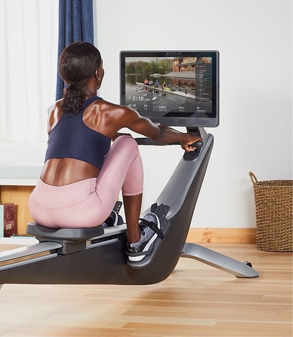a woman with black skin looking at the monitor screen of Hydrow magnetic rowing machine