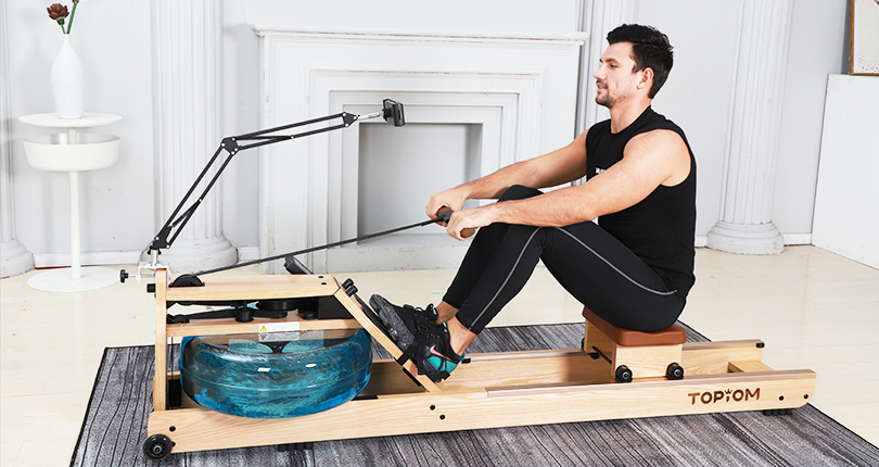 a man looks at a device put at his eye level while rowing in a room